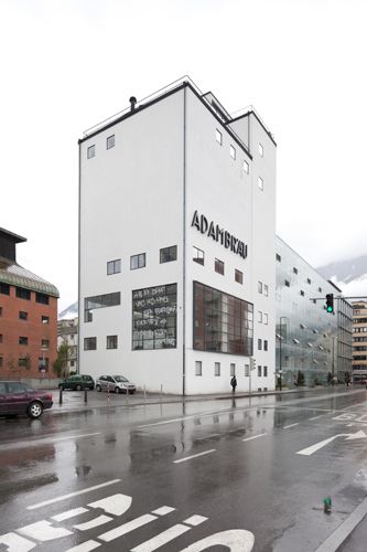 Michl Schmidt + Peter Wendl: Verteidigung des Normalzustands – Haussegen an der Fensterfront des Adambräu:
"Herr, behuete uns dies Haus fuer Feuersnoth,
fuer Pest und den boesen schnellen Todt."